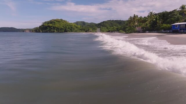 Punta Potrero, Costa Rica with ocean view and mountains with drone video pulling back low along beach.