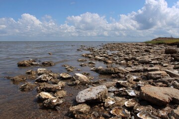 Coastal scene with rocky shore calm water and a cloudy blue sky