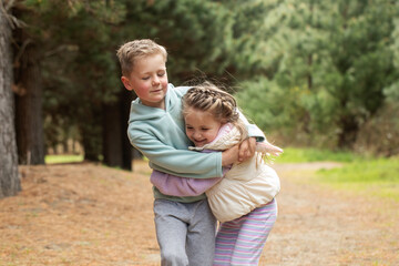 A touching embrace between a brother and sister on a trail in a pine forest. Famil, happy siblings