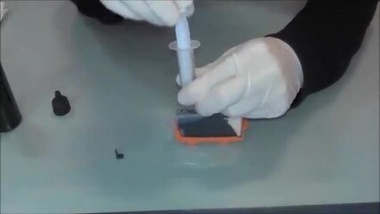 Close-up of syringe gently injecting ink into cartridge, showcasing smooth, controlled motion and clean refill process. Ideal for DIY printer maintenance and ink refill tutorials