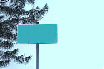 Blank Green Street Sign with Tree and Bright Sky Background