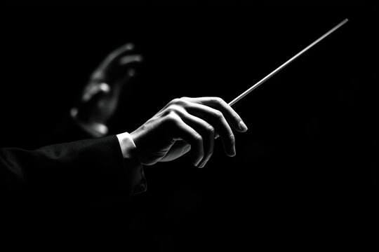 Hands of a conductor against a dark backdrop