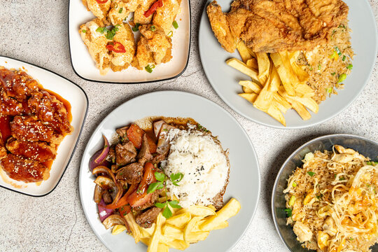 Peruvian chifa food with lomo saltado, rice, french fries, and fried chicken dishes on plates