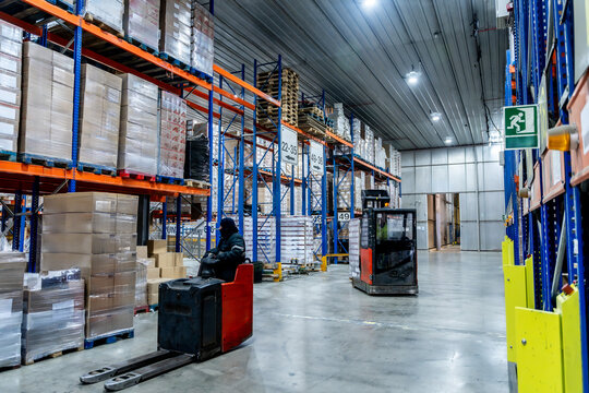 Workers operating forklifts in cold storage logistics warehouse
