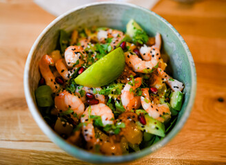 Bowl of salad with fresh shrimp, lemon, and cilantro