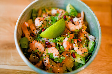 Bowl of salad with fresh shrimp, lemon, and cilantro