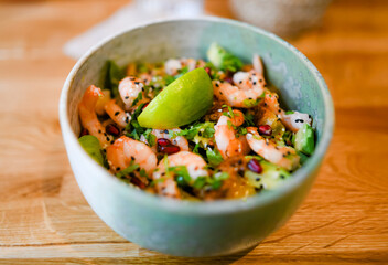 Bowl of salad with fresh shrimp, lemon, and cilantro