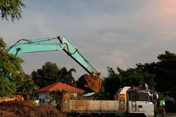 This image captures the industrial process of excavation, where a hydraulic backhoe transfers a...