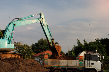 This image captures the industrial process of excavation, where a hydraulic backhoe transfers a...