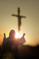 Christian silhouettes raising their hands toward the cross of Jesus Christ, praying in sorrow, Holy Week background
