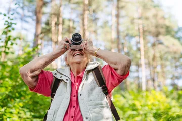 Fotobehang Muziek Elderly woman photographing nature during forest walk.  © Halfpoint