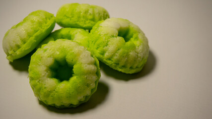 Close-up of a traditional Indonesian cake called putu ayu, a sweet, fragrant cake topped with coconut—white background.