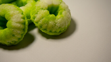 Close-up of a traditional Indonesian cake called putu ayu, a sweet, fragrant cake topped with coconut—white background.