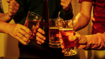 Close up friends hands clinking beer glasses in warm golden light, celebrating friendship teamwork. A joyful moment filled with laughter, unity, positive energy during relaxing evening gathering.