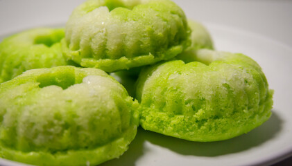 Close-up of a traditional Indonesian cake called putu ayu, a sweet, fragrant cake topped with coconut—white background.