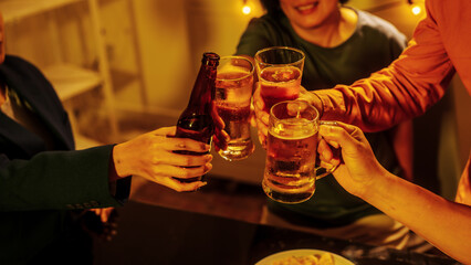 Close up friends hands clinking beer glasses in warm golden light, celebrating friendship teamwork. A joyful moment filled with laughter, unity, positive energy during relaxing evening gathering.