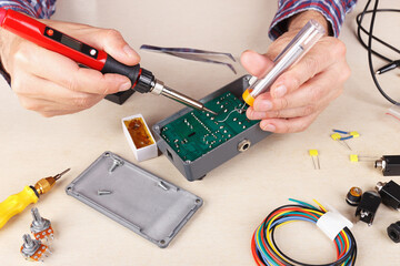 Electronics engineer solder electrical hardware at service workplace.
