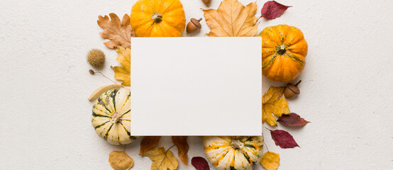Autumn composition with paper blank and dried leaves with pumpkin on table. Flat lay, top view, copy space