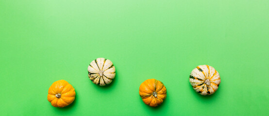 Autumn composition of little orange pumpkins on colored table background. Fall, Halloween and Thanksgiving concept. Autumn flat lay photography. Top view vith copy space