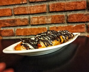 fried bananas with chocolate and cheese topping on a leaf-shaped plate