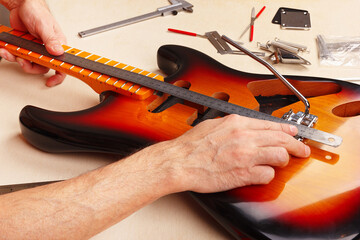 Guitar technician measures distance of tremolo installation on electric guitar.