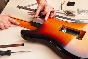 Guitar technician sets neck plate on electric guitar.