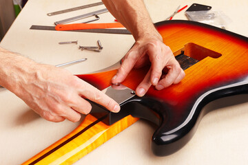 Guitar repairman sets neck plate on electric guitar.