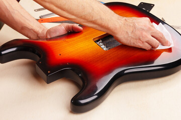 Guitar technician polishes body of electric guitar.