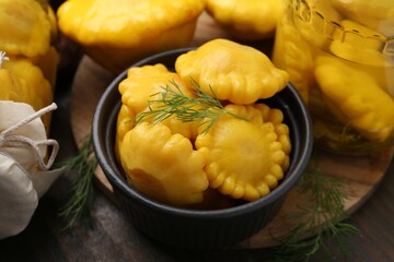 Pickled pattypan squashes and dill on wooden table, closeup