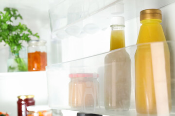 Bottles with different tasty sauces and products in fridge, closeup