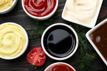 Different sauces and herbs on wooden table, flat lay