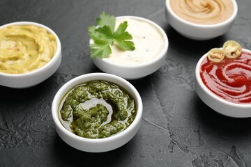 Different sauces and parsley on black table, closeup