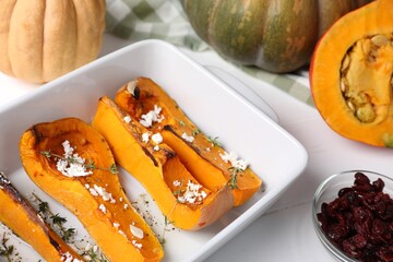 Baked pumpkin and ingredients on white wooden table, closeup