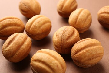 Delicious nut shaped cookies with boiled condensed milk on brown background, closeup