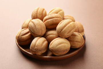 Delicious nut shaped cookies with boiled condensed milk on brown background, closeup