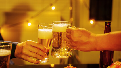 Close up friends hands clinking beer glasses in warm golden light, celebrating friendship teamwork. A joyful moment filled with laughter, unity, positive energy during relaxing evening gathering.
