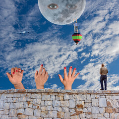 Surreal scene with a man climbing a ladder from a hot air balloon to the moon with eyes, three hands reaching from a stone wall toward the sky, airplane flying across dreamy clouds.