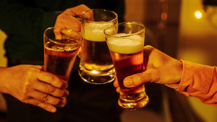 Close up friends hands clinking beer glasses in warm golden light, celebrating friendship teamwork. A joyful moment filled with laughter, unity, positive energy during relaxing evening gathering.