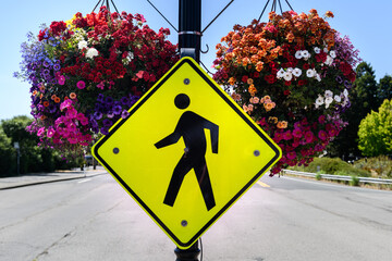 Yellow traffic warning sign marking a crosswalk and alerting motor vehicle drivers to exercise caution as pedestrians may be walking across the street.