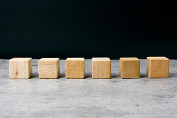 Six blank wooden blocks in a row on table with blank space for your text, letters or numbers.