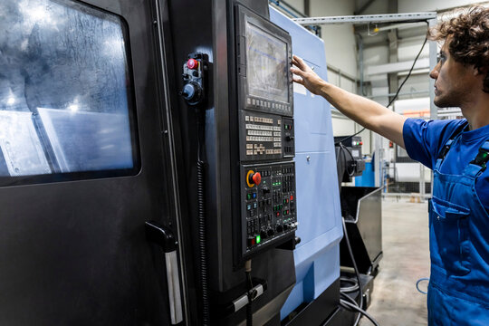 Technician operating and programming robotic machinery in metal industry