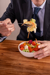 Businessman enjoying a fresh salad during a lunch meeting at a wooden table