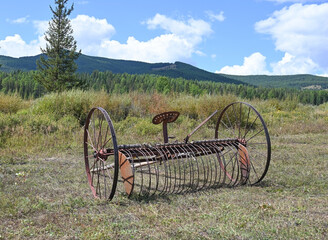 Old farm hay mower in a field