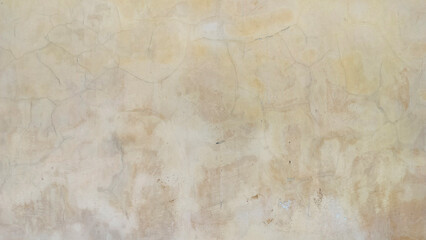 Old cracked wall with peeling paint and faded stains. Vintage beige plaster surface texture with weathered and aged details. Perfect grunge background for design, construction, or retro concept.
