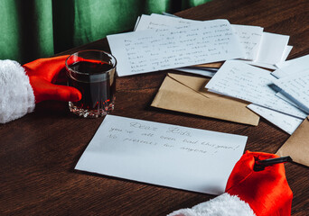 Santa Claus writing humorous Christmas letter with whiskey on table