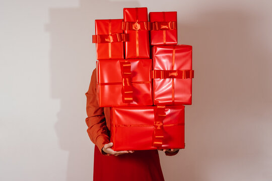 Housewife humorously overwhelmed by stack of red Christmas gifts