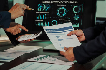 Business professionals closely review a balance sheet and digital Global Investment Portfolio data, pointing to key figures, indicating strategic financial planning and rigorous cash flow management.