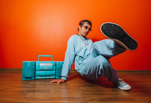 Breakdancer in blue tracksuit with boombox against orange wall