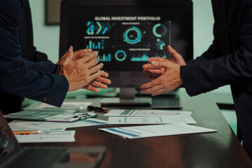 Business professionals closely review a balance sheet and digital Global Investment Portfolio data,...