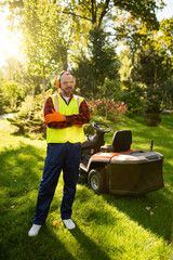Fototapeta premium Confident man gardener posing with grass mower